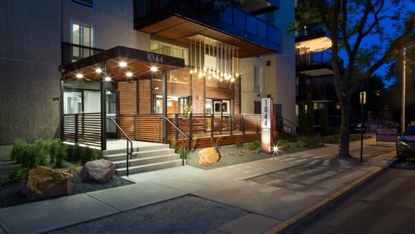 1044 Downing entrance at night with brightly lit community patio and large balconies.
