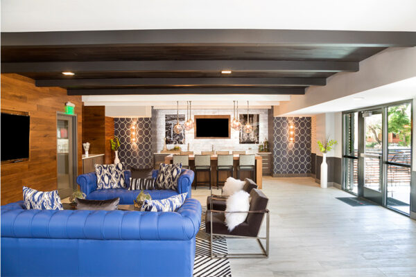 Lounge with wall mounted TV, plush loveseats, modern chairs, and eclectic decor.