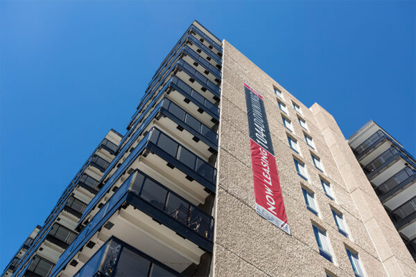 1044 Downing apartment building with large balconies under blue skies.