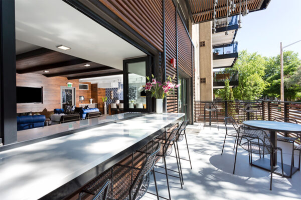 Indoor outdoor lounge with sliding windows and comfortable furniture.