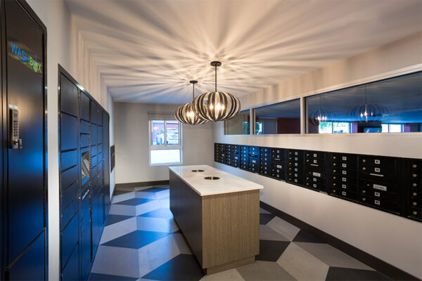 Mail room with geometric tile floors, mailboxes, round ceiling lamps, and smooth table.