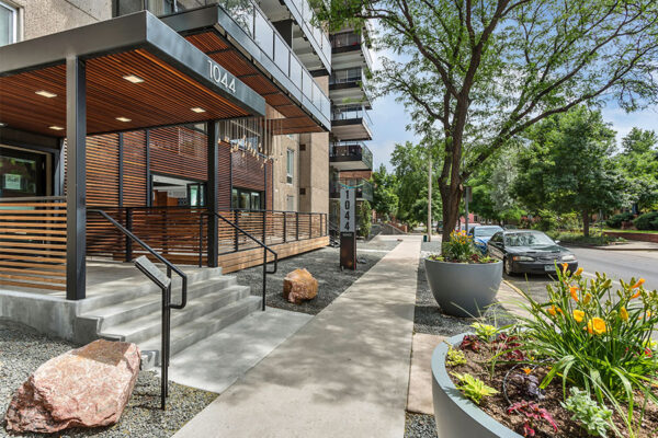 1044 Downing apartment building with slatted wood patio, wide sidewalks, and street parking.