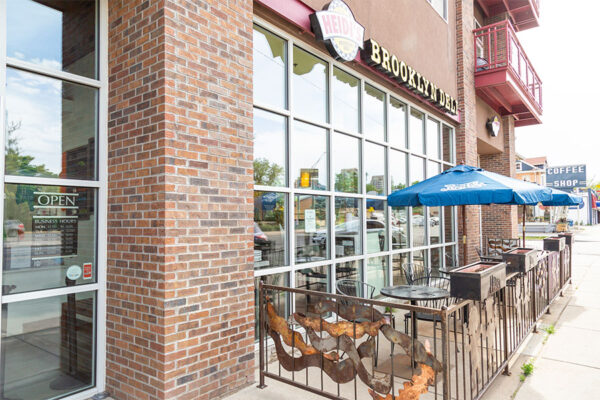 Heidi's Brooklyn Deli restaurant with glass wall and patio with umbrellas.