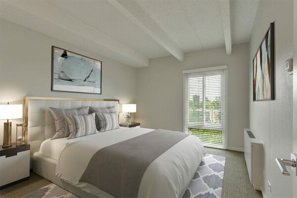 Bedroom with large bed with plush headboard, bedside tables with lamps, large window, and artwork.