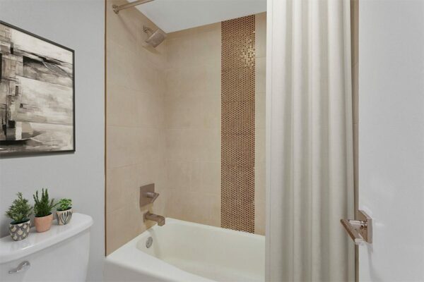 Bathroom with tiled shower tub, curtain, and framed artwork.