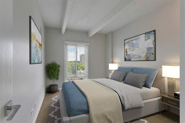 Bedroom with large bed, bedside tables with lamps, large window, and framed artwork.