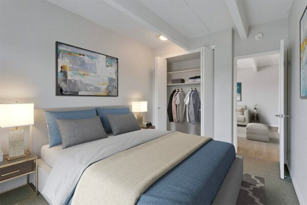 Bedroom with large bed, bedside tables with lamps, large closet, and framed artwork.