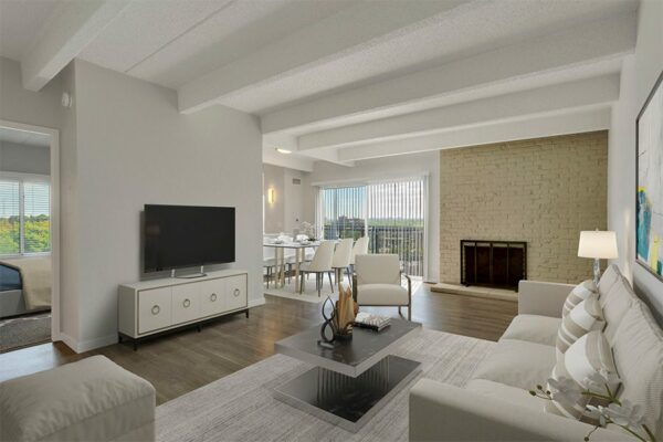 Living room with wood floor, plush couch, modern furniture, and brick accent wall with fireplace.