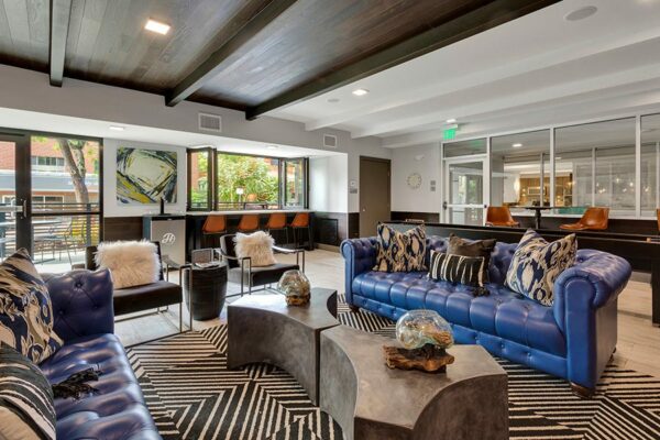 Lounge with geometric rug, modern furniture, plush leather seating, and large windows.