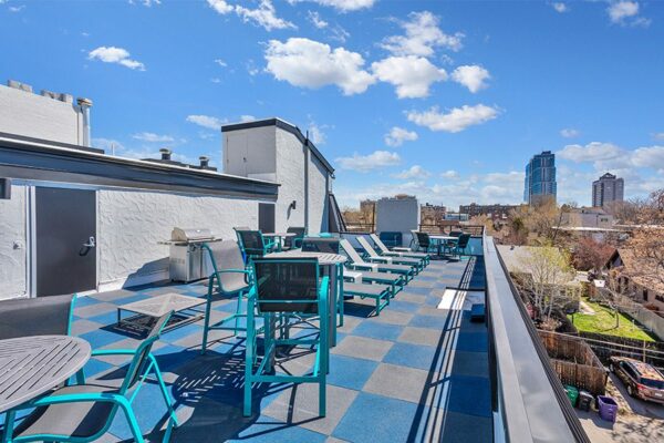 Rooftop patio with lounge chairs, tables, and BBQ grill overlooking Denver.