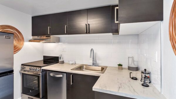 Kitchen with dark cabinets, stone counter, stainless steel appliances, and wall art.