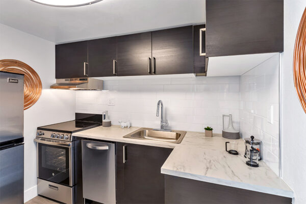 Kitchen with dark cabinets, stone counter, stainless steel appliances, and large copper wall art.