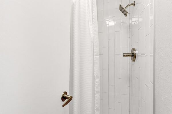 White tiled shower with curtain.