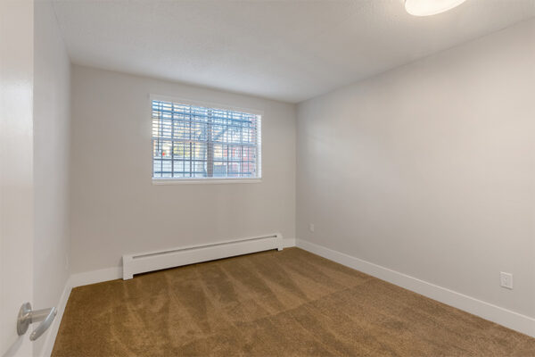 Bedroom with plush carpet and large window.