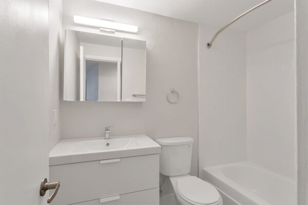 Bathroom with white cabinets and counter and tiled shower tub.
