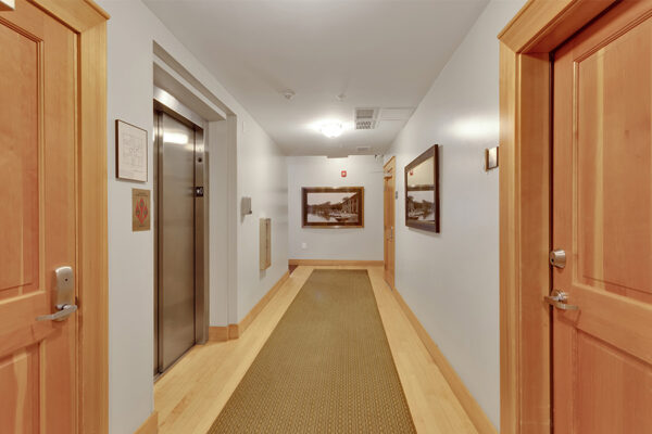 Lobby with wood floors, carpet runner, wood doors, and elevator.