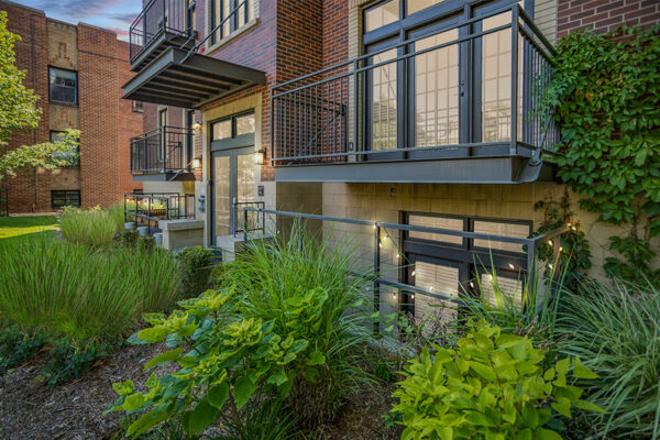 1145 Ogden apartment building with lush landscaping, brick construction, and large balconies.