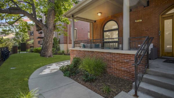 Porch area with brick construction, wide paved pathways, and lush landscaping.