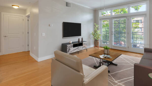 Living room with wood style floor, plush seating, wall mounted TV, and balcony door.