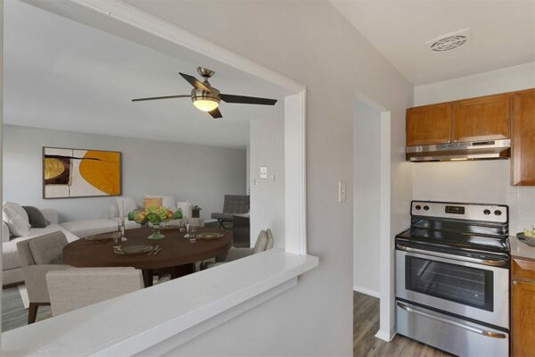 Kitchen with wood cabinets, stainless steel appliances, and window to dining and living room.