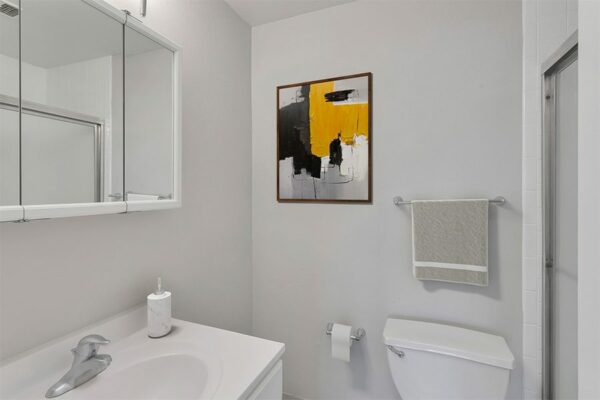 Bathroom with white cabinets and counter and framed artwork.