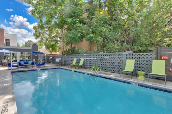 1190 Birch pool area with clean blue water, lounge chairs, and tables with umbrellas.