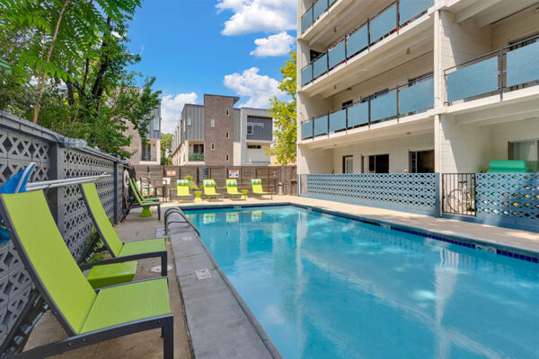 1190 Birch pool area with clean blue water and lounge chairs overlooked by apartment balconies.