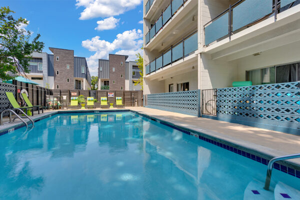 1190 Birch pool area with clean blue water and lounge chairs overlooked by apartment balconies.