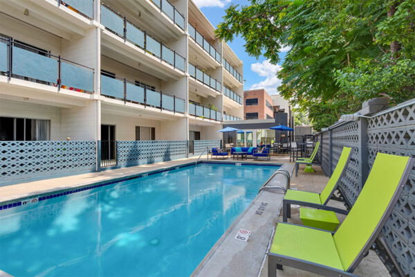 1190 Birch pool area with lounge chairs and tables overlooked by apartment balconies.