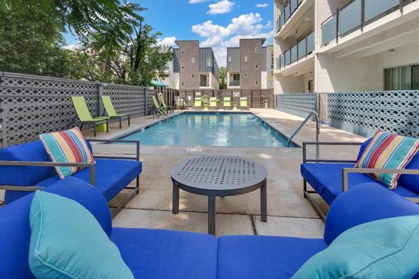 Pool area with lounge chairs, outdoor sectional, and decorative cinderblock walls.