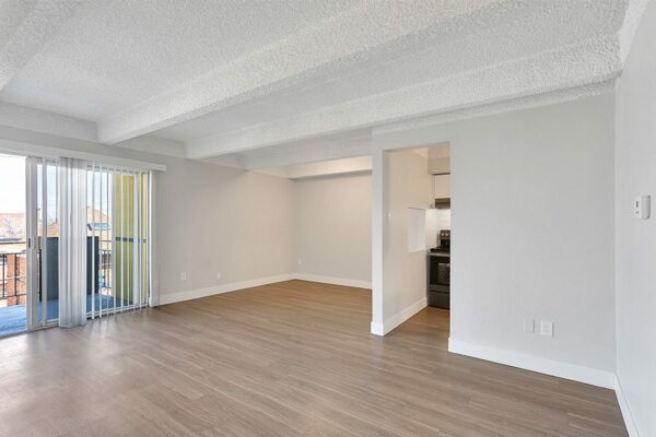 Living area with wood floor, grey walls, white trim, and sliding door to balcony.