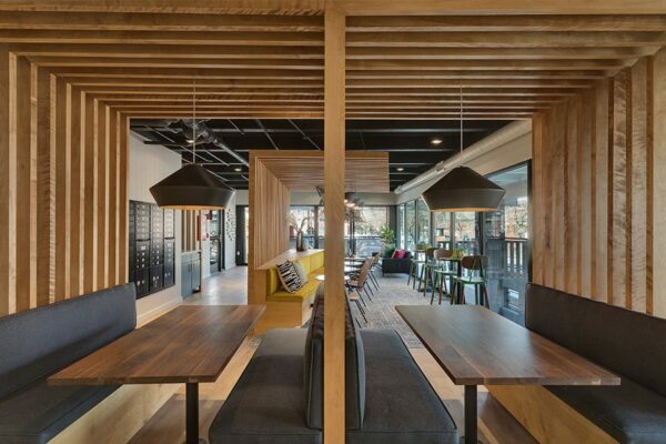 Lounge with wood floors, built in booths with decorative slats, and large windows.