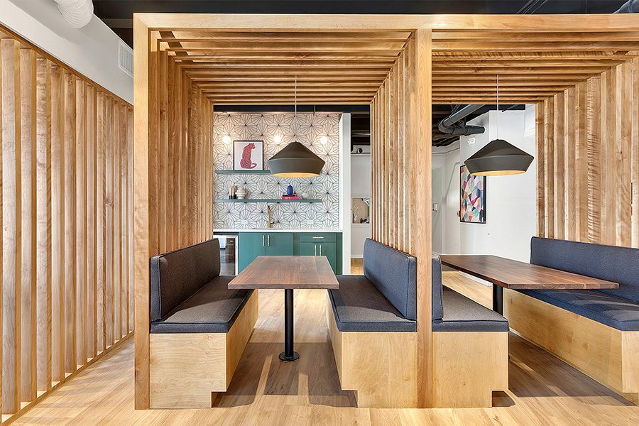 Lounge with wood floors, built in booths with decorative slats, and large windows.