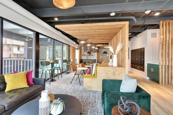 Lounge with comfortable modern furniture, eclectic decor, mailboxes, and large windows.