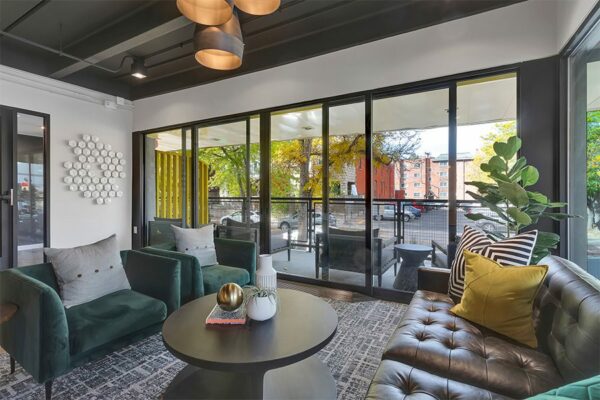 Lounge with geometric carpet, plush seating, eclectic decor, and large window.