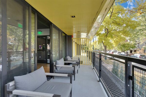 Balcony with metal railing, plush chairs, and door to lounge.