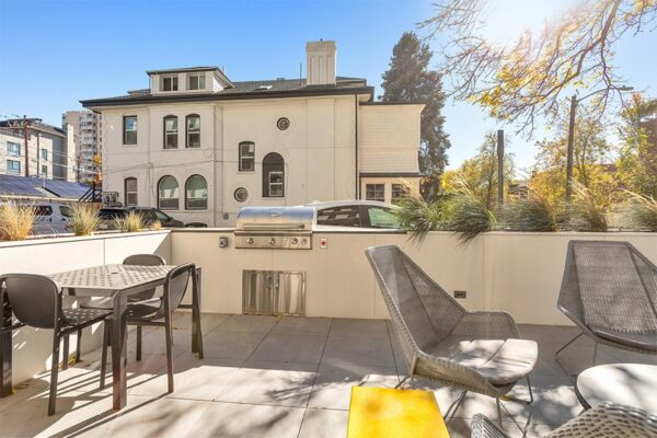 Outdoor lounge with seating, built in BBQ grills, and lush landscaping.