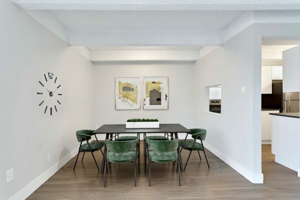 Dining room with wood floor, modern table with chairs, built in wall clock, and artwork.