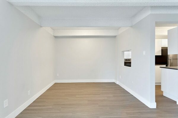 Dining room with wood floor, grey walls, white trim, and opening to kitchen.