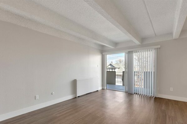 Living room with wood floor, grey walls, white trim, and sliding door to balcony.