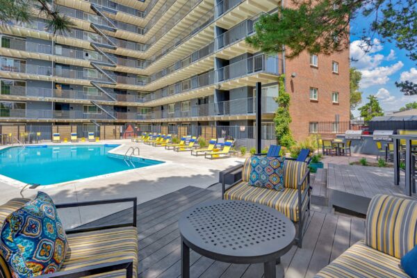 Pool area with lounge chairs and built in BBQ grills overlooked by apartment balconies.