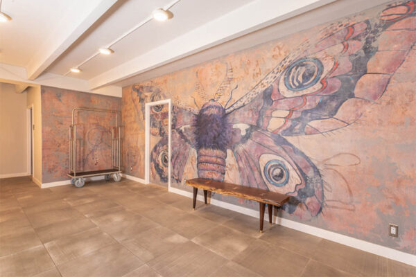 Indoor mural depicting large painted moth with live edge wood bench.