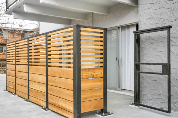 Patio with slatted fence and large metal gate.