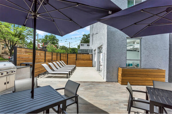 Outdoor patio with umbrellas, tables, lounge chairs, and built in BBQ grill.