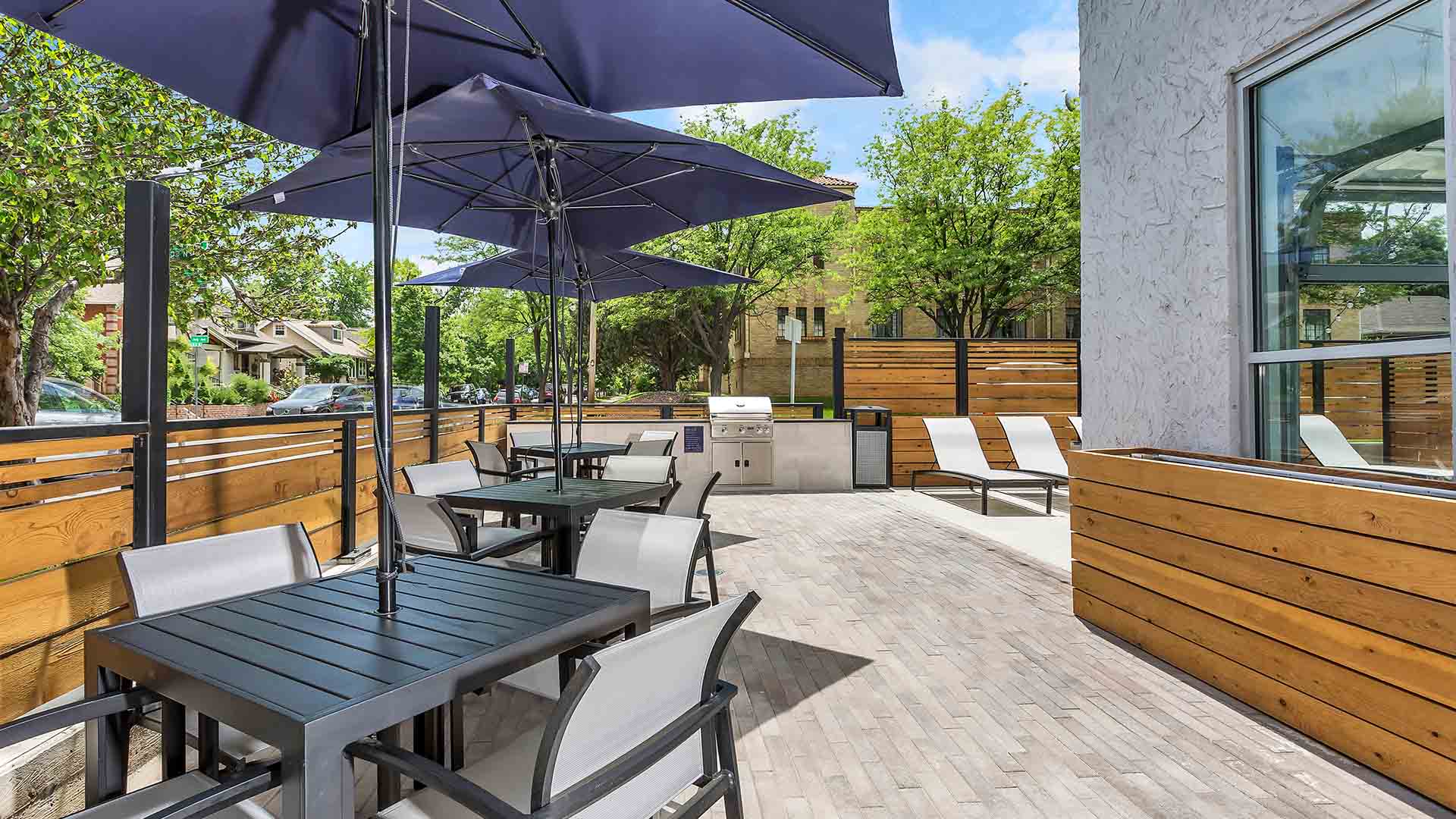 Patio with tables with umbrellas, table tennis, BBQ grill, and garage doors to indoor pool.