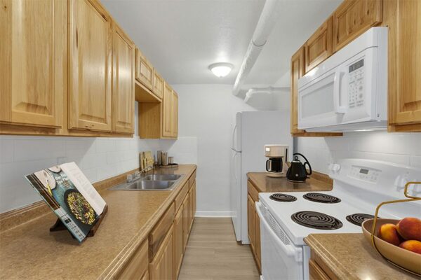1357 & 1373 Cook kitchen with wood cabinets, stone counters, and white appliances.
