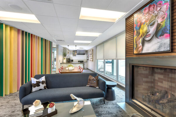 Lounge with comfortable plush couch, eclectic decor, large fireplace, and colorful painting.