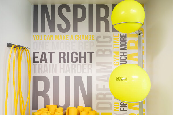 Inspirational fitness center wall graphic behind exercise balls and bands.