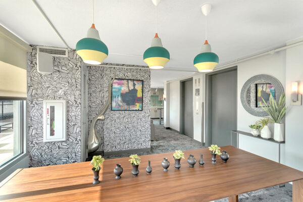 Lounge with carpet, eclectic decor and artwork, large sculpture, and large windows.