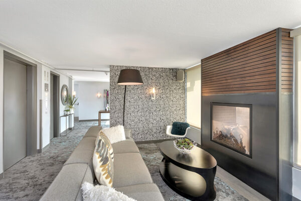 Lounge with carpet, modern furniture, and large fireplace.